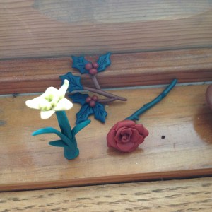 A daffodil, a rose, and holly made of polymer clay